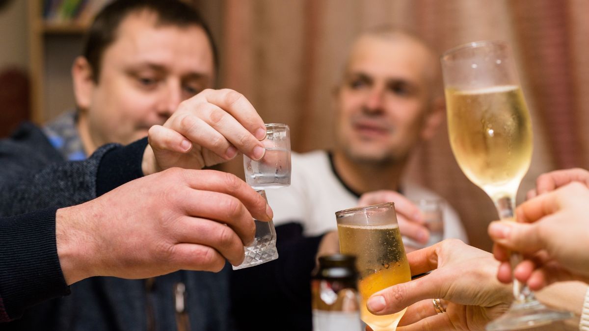 Több ember koccint alkoholos italokkal egy baráti összejövetelen.
