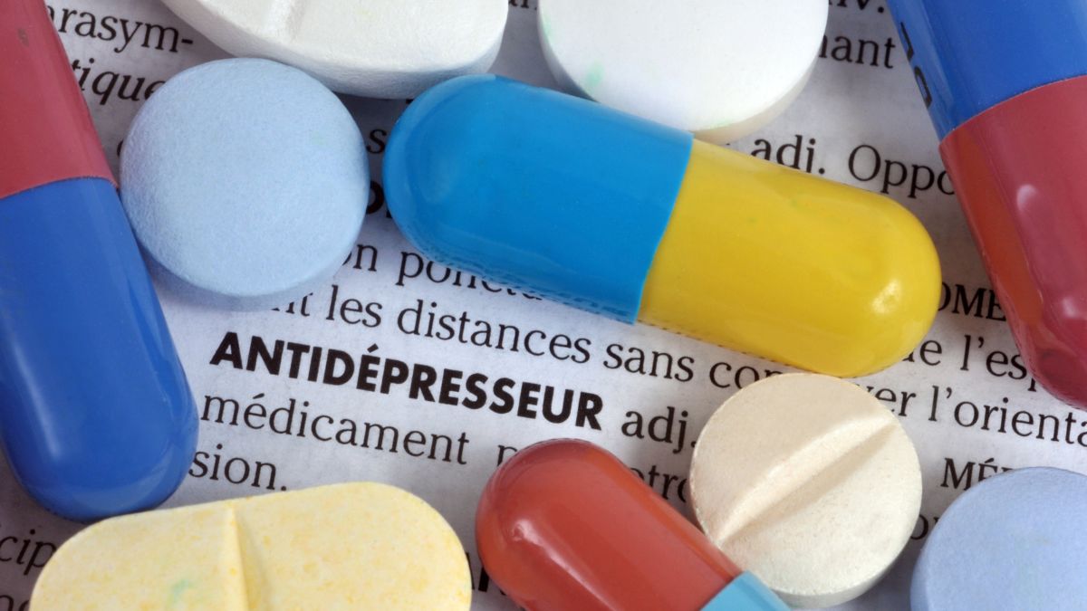 Különböző színű antidepresszáns tabletták egy újságcikk felett.