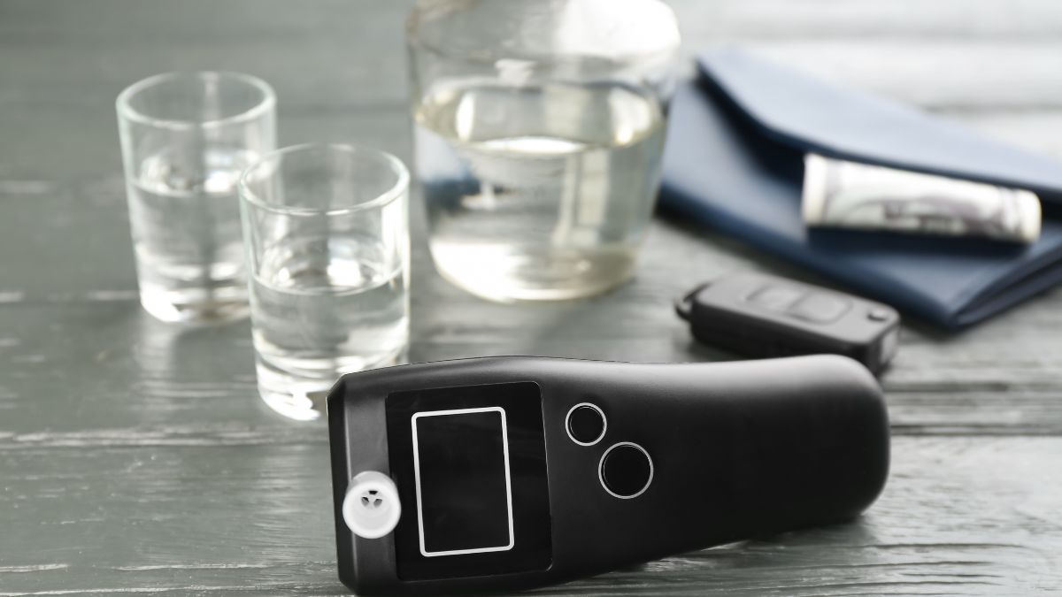 Egy digitális alkoholszonda, víz és egyéb tárgyak mellett az asztalon.