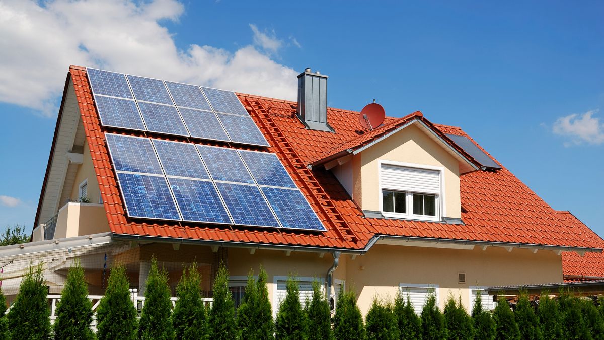 Egy ház tetején napkollektorok találhatók, zöld energia hasznosítására.