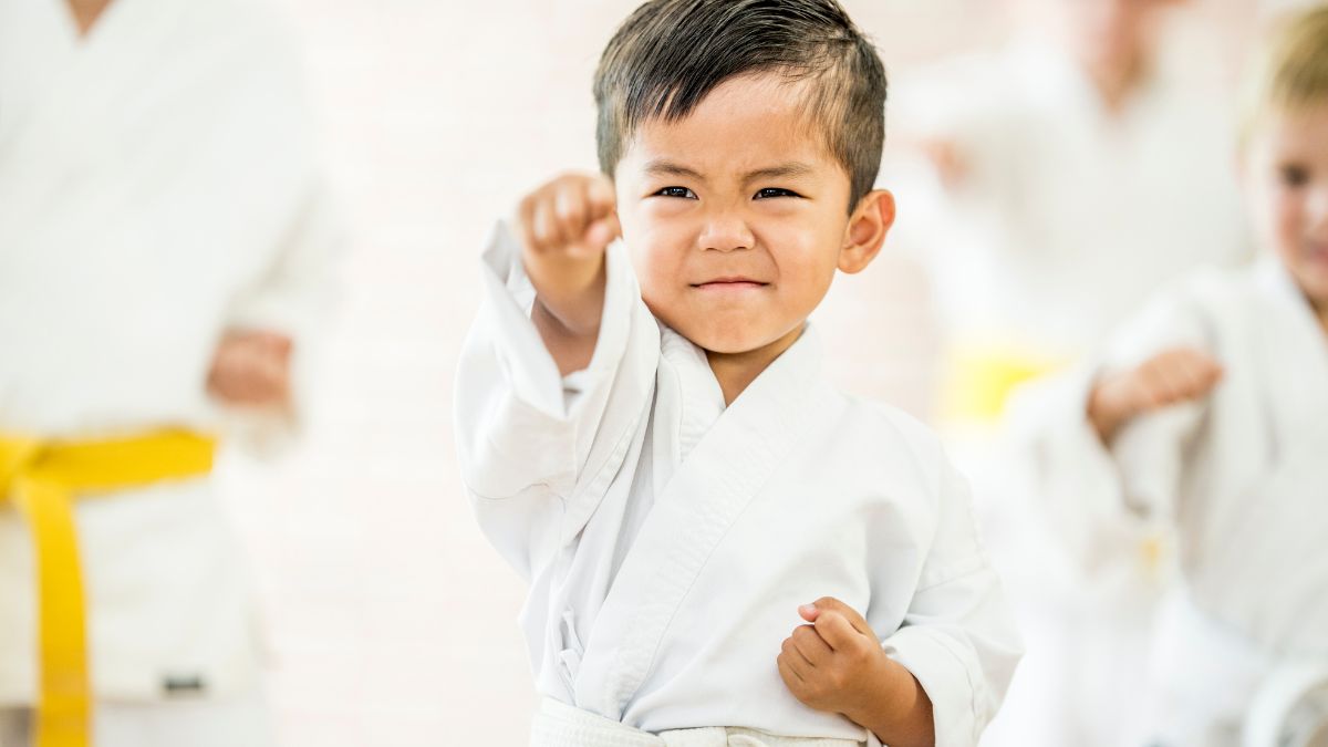 Egy kisfiú karate edzés közben, fehér gi-ben, határozott arckifejezéssel.