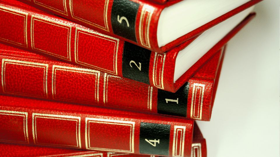 Piros borítójú lexikonok egymásra helyezve, számokkal jelölve.