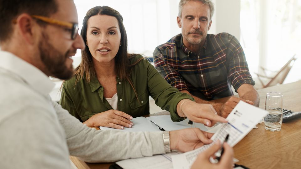 Egy nő aktívan kommunikál egy férfival, míg egy másik férfi figyelmesen hallgat.